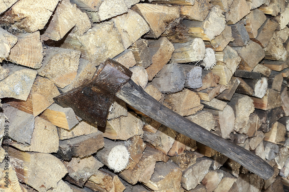 Split a log with an ax. Birch firewood in the background. Wood wallpaper. Hatchet. Split a log with an ax. Birch firewood in the background. Wood wallpaper. Hatchet.