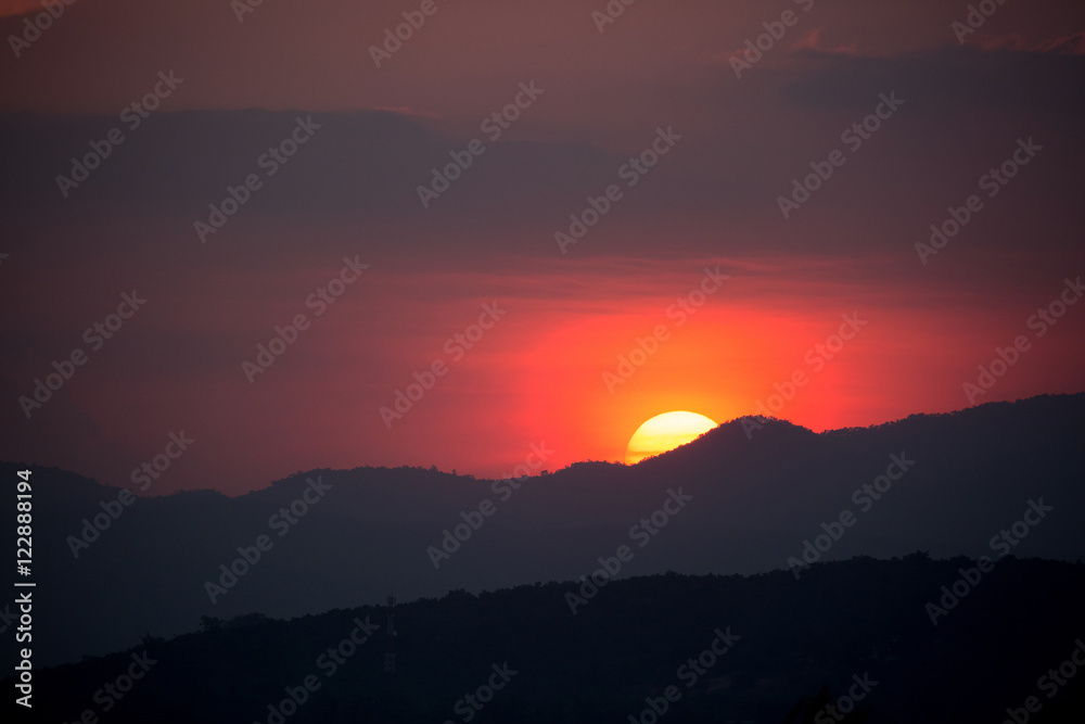 Piece of sun behind the mountains at sunset