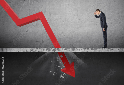 Canvas Print Businessman looking down at the falling red arrow destroying a concrete barrier