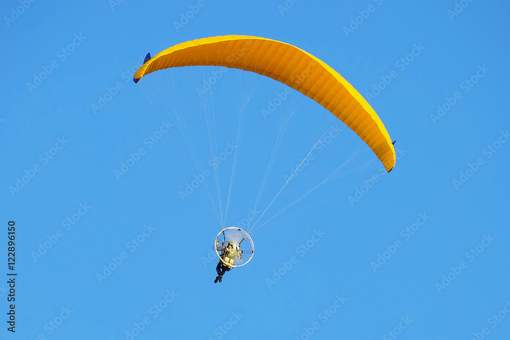 Flight on a motorized paraglider. Yellow paraglider with a paramotor. Flight on a motorized paraglider. Yellow paraglider with a paramotor.