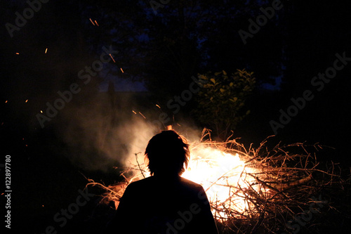 Glowing ember sticks campfire at night with flames silhouette watching peacefully Hygge