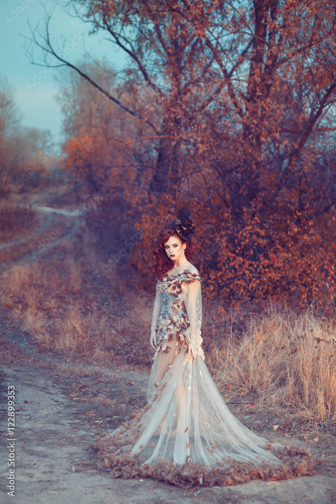 Red hair girl in beautyful fasion dress standing at the yellowed tree Red hair girl in beautyful fasion dress standing at the yellowed tree