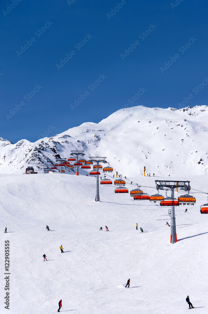Skiers and orange chairlift in Alpine ski resort in Solden in Otztal Alps, Tirol, Austria