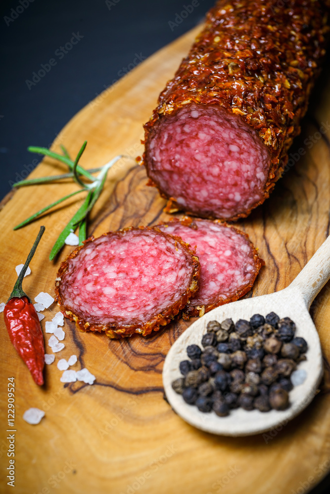 dried salami crusted in ground red pepper on dark background dried salami crusted in ground red pepper on dark background
