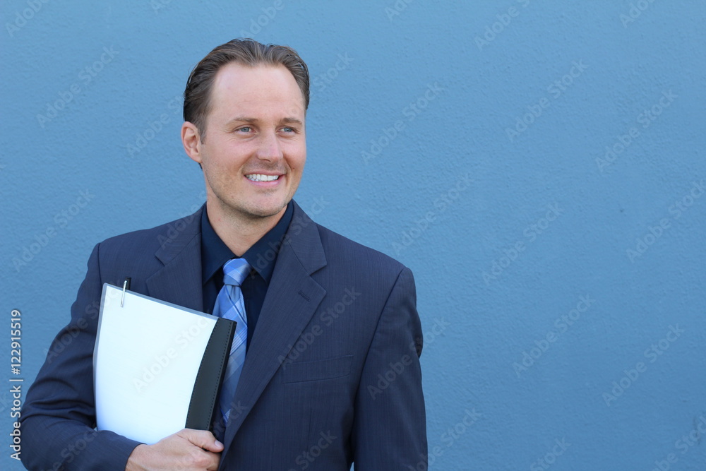 Happy businessman holding documents isolated on blue looking away towards the side. Smiling with satisfaction. Happy businessman holding documents isolated on blue looking away towards the side. Smiling with satisfaction.