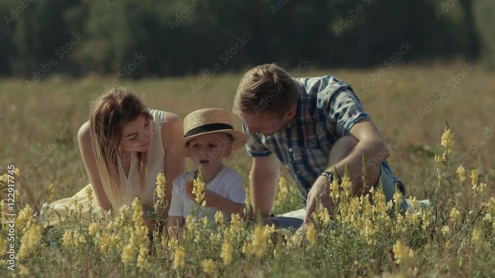 Happy loving family enjoying their time in nature. Parents bend to kiss their adorable child Happy loving family enjoying their time in nature. Parents bend to kiss their adorable child