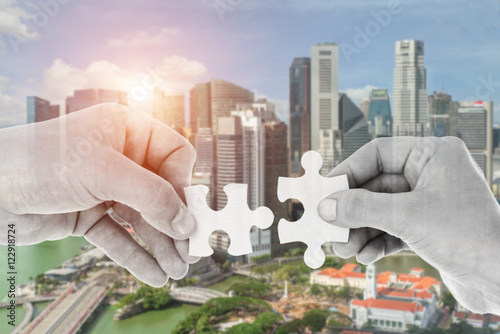 Canvas Print Hands putting partnership puzzle pieces together on skyscraper