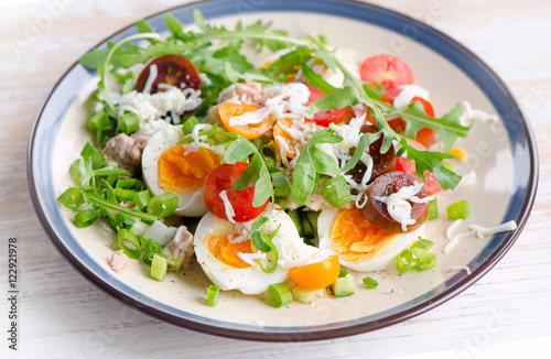 Fresh salad with fish, eggs and tomatoes in plate.