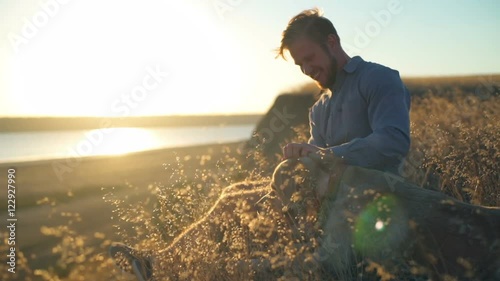 happy male gently caressing old dog in field on sunset