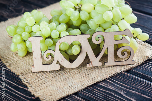 Wood inscription LOVE and green grapes