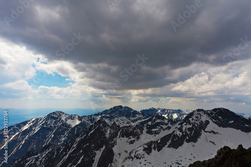 High snowy mountains under blue cloudy sky © lukszczepanski