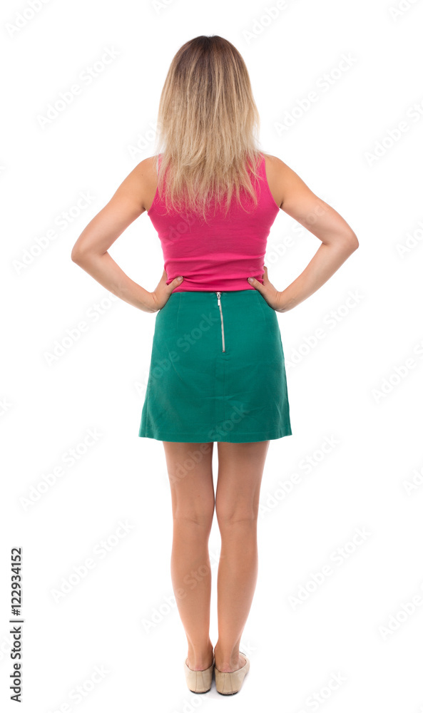 back view of standing young beautiful  woman.  girl  watching. Rear view people collection.  backside view of person.  Girl in green skirt standing with hands on waist.
