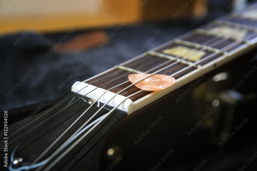 Fototapeta premium Acoustic guitar with piectrum close up in dark background