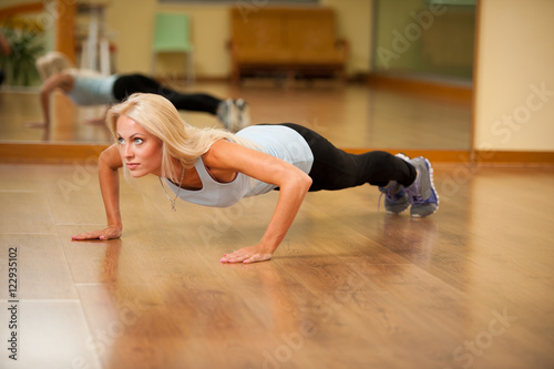 Fit woman works out in gym making push ups