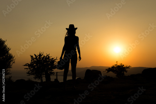Silhouette capture of a woman with cowboy hat on hill at sunset