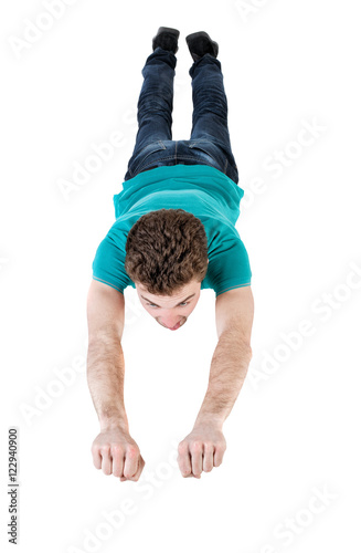 Flying man . Smiling curly-haired guy is flying in Superman pose.   Isolated over white background. Top view of the flying man.