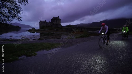 Cyclists on a long distance 24 hour bike ride pull into the car park at Castle Eilean Donan at dawn. Scottish Highlands, near  Kyle of Lochalsh. photo