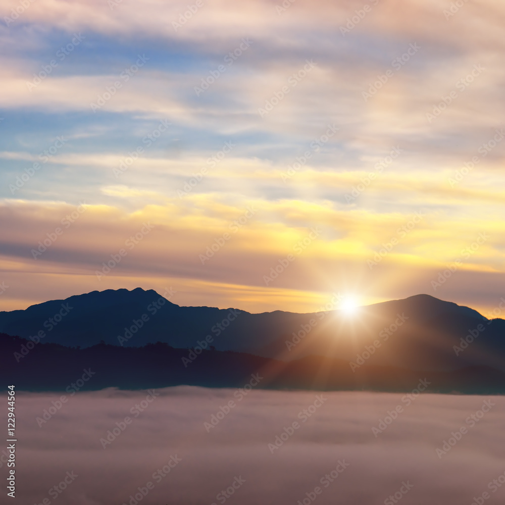 Bright sunrise, the mist in a mountain valley and mountain peaks