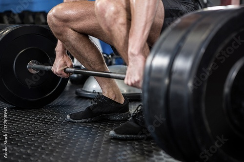 Low section of man lifting barbell