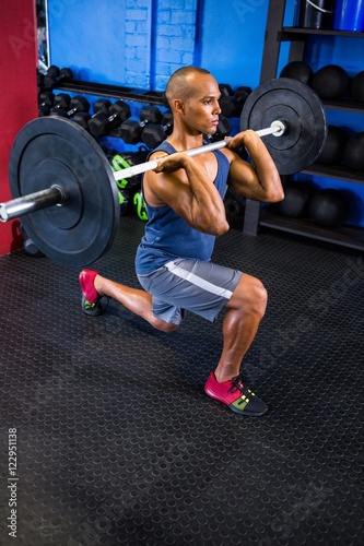 Determined man lifting barbell in fitness studio