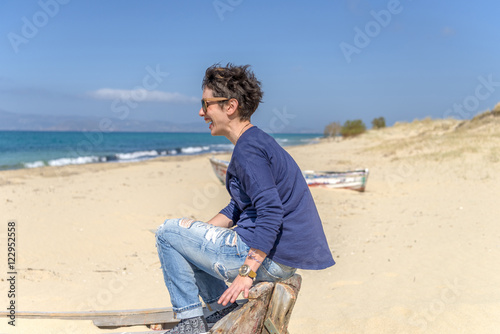 Young woman on stylish outfit sitting on an abandoned fishing bo