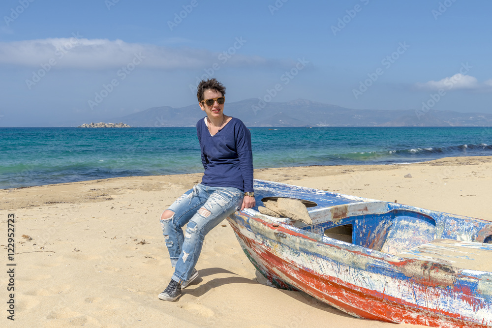 Young woman on stylish outfit sitting on an abandoned fishing bo