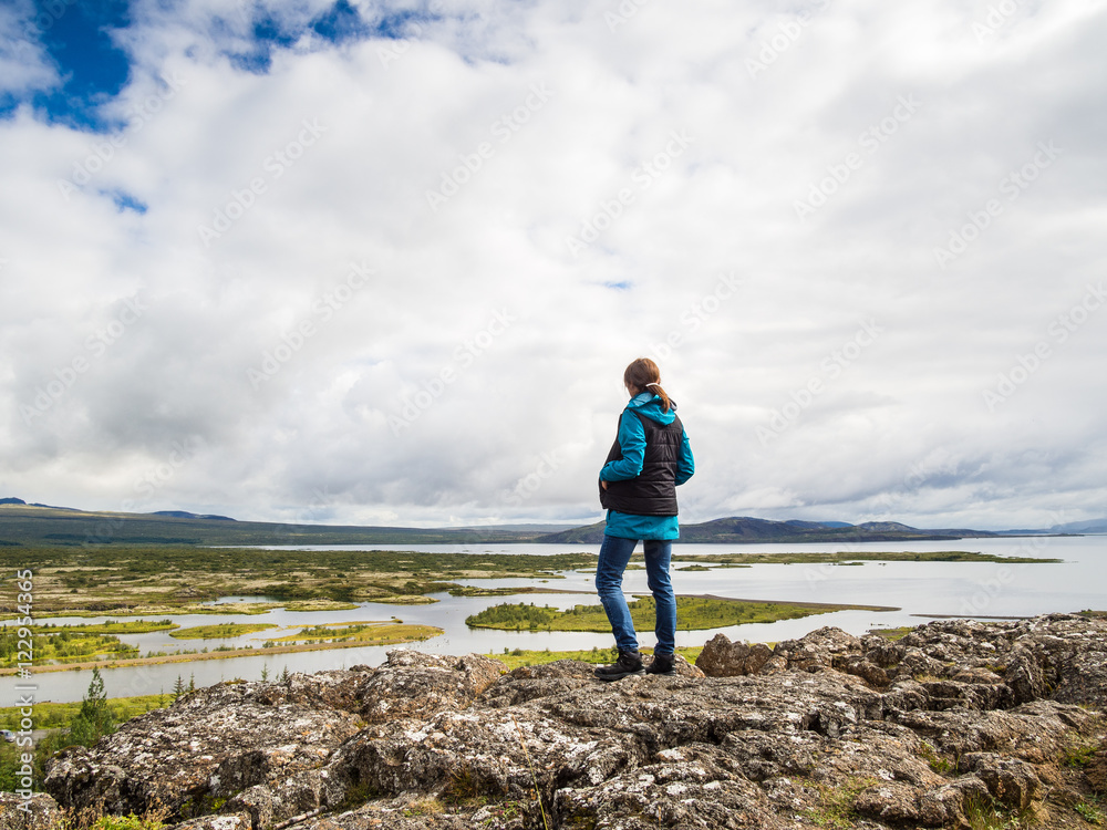Woman is standing at a cliff in front of the Thingvellir Nationa