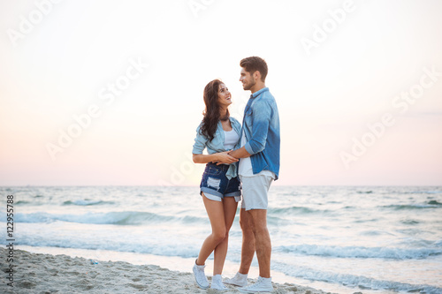 Beautiful young couple standing and laughing on the beach