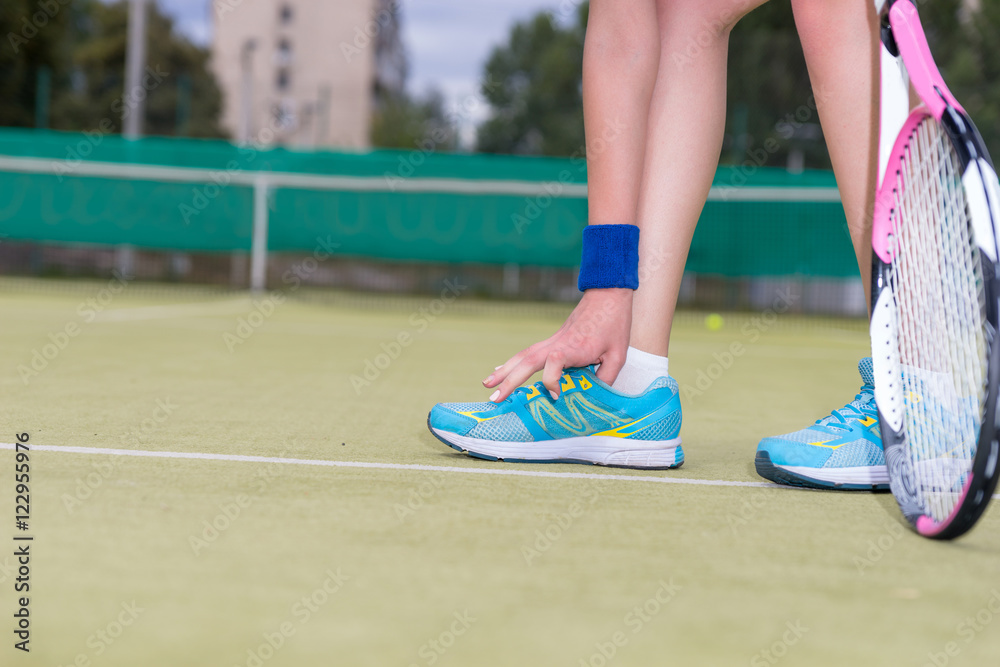 Woman tying shoelaces during tennis match Woman tying shoelaces during tennis match
