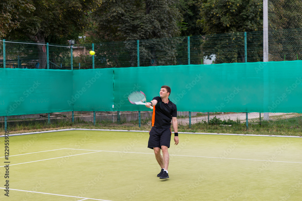Fototapeta premium Confident young man in sports clothes playing tennis