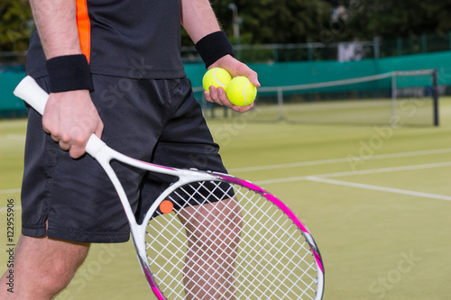 Close-up of man holding tennis balls and racket © kolotype