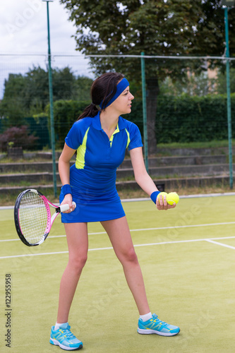 Young female tennis player preparing to serve wearing a sportswe