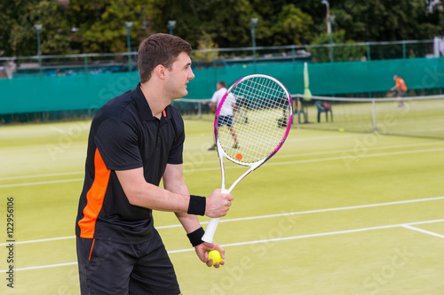 Male tennis player is ready to throw ball