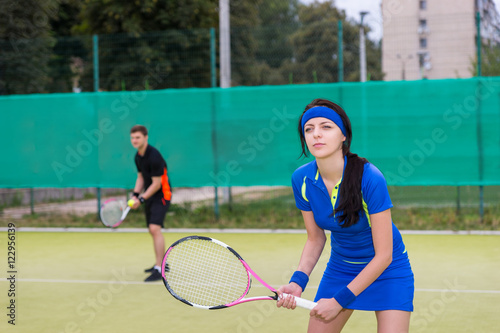 Female and male tennis players playing doubles outdoors