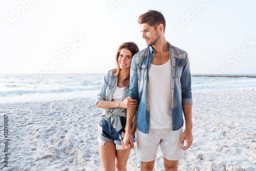Beautiful couple holding hands and walking at the beach