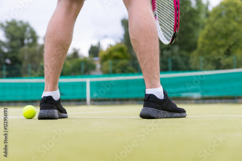 Male tennis player's legs during the game on green grass court o