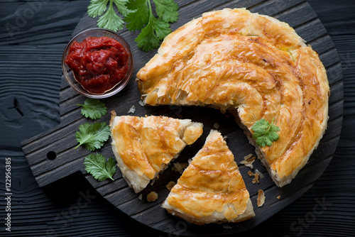Foto Burek pie with meat stuffing on a black wooden serving board