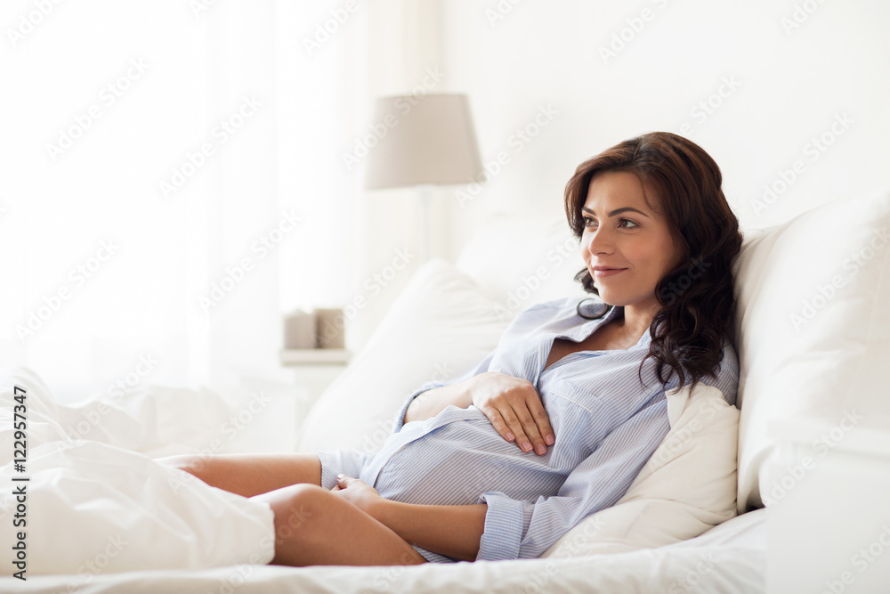 happy pregnant woman lying on bed at home happy pregnant woman lying on bed at home