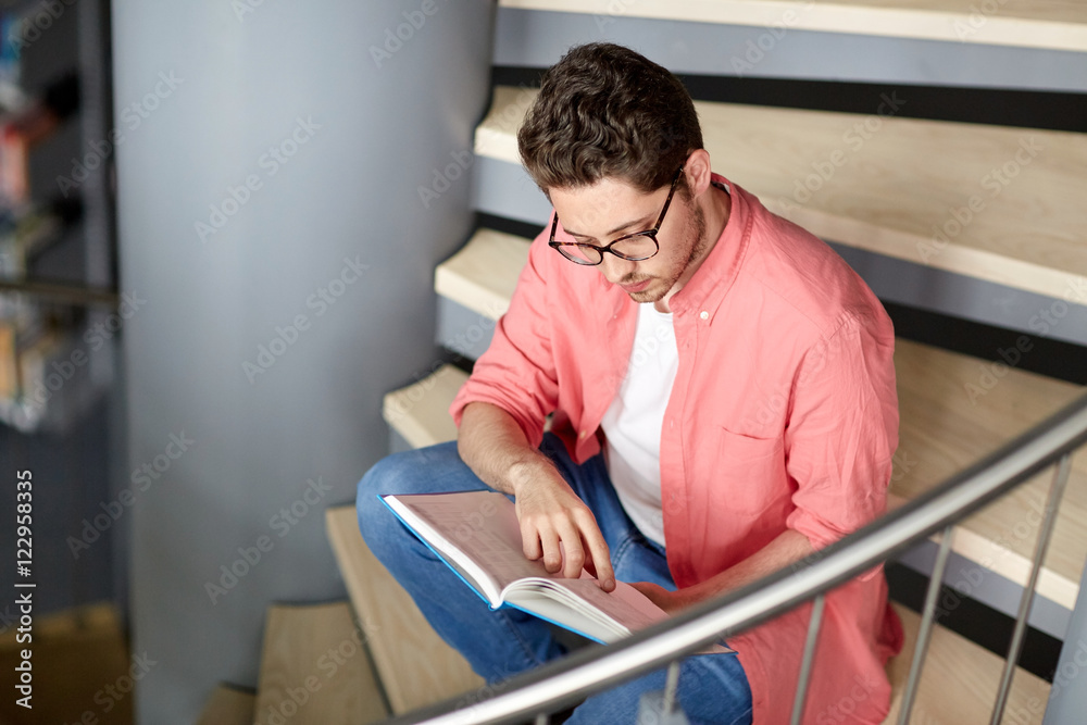 student boy or young man reading book at library