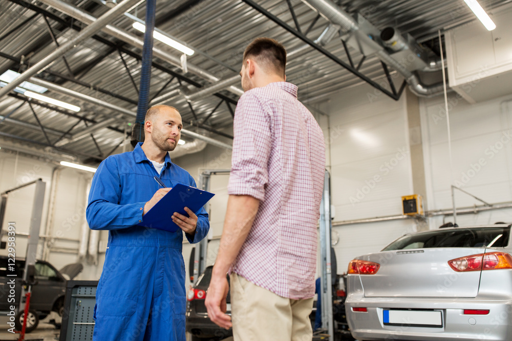 auto mechanic with clipboard and man at car shop