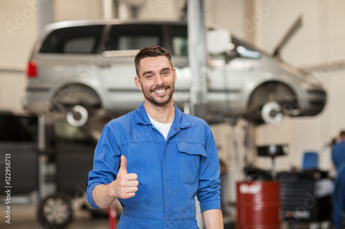 happy auto mechanic man or smith at car workshop photo