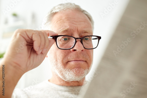 Fotografi close up of old man in glasses reading newspaper