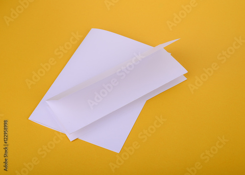 white paper bifold and four-fold brochure mockup on yellow backg