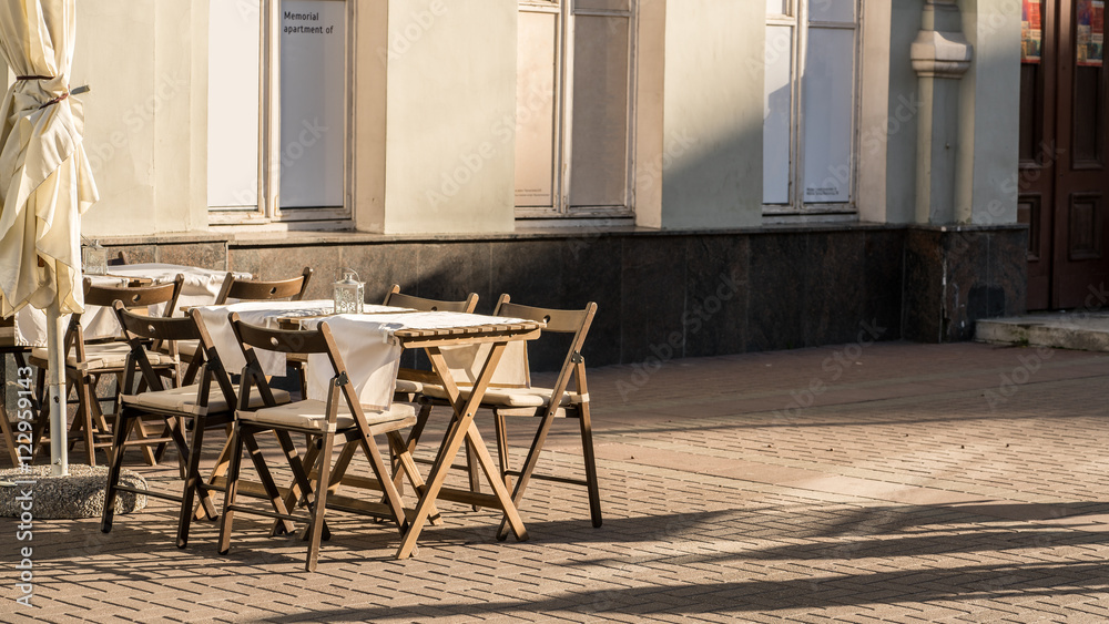 Naklejka premium Light and shadow of tables placing outside restaurant waiting for customers in the evening on walking street so called Arbat street , Moscow , Russia