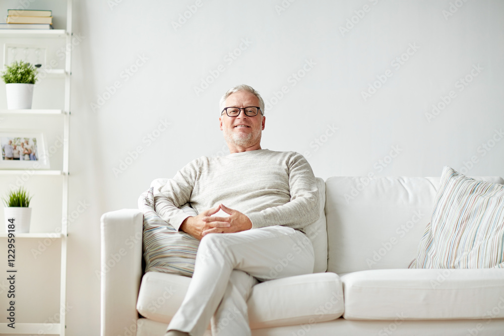 smiling senior man in glasses sitting on sofa smiling senior man in glasses sitting on sofa