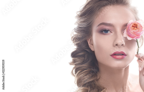 Beautiful girl in image of bride with flower. Model with nude makeup and a rose in her hand. Beauty face. Photo was taken in a studio.