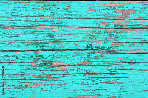 Texture of old wooden planks with cracked turquoise paint closeup