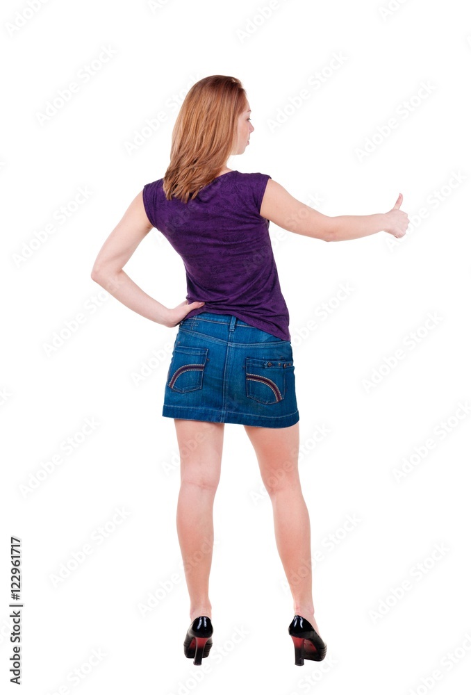 Back view of of young woman in jeans dress going thumb up. girl showing ok sign. isolated on white Rear view.Showing of positive emotions with OK sign concept . Back view of of young woman in jeans dress going thumb up. girl showing ok sign. isolated on white Rear view.Showing of positive emotions with OK sign concept .