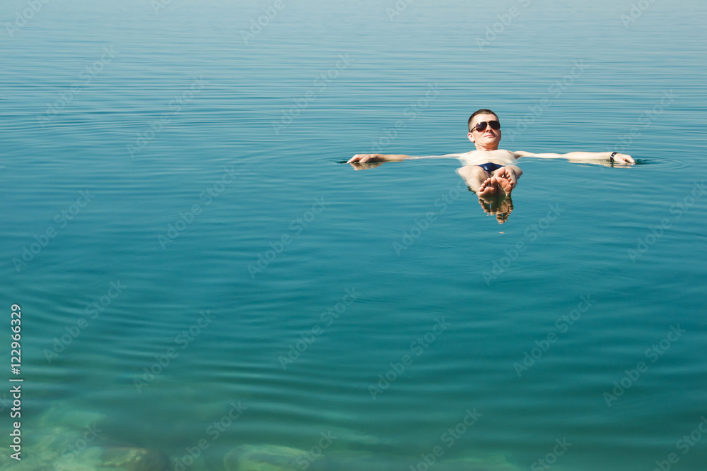 Man floating in water Dead Sea. Tourism recreation, healthy lifestyle concept. Copy space