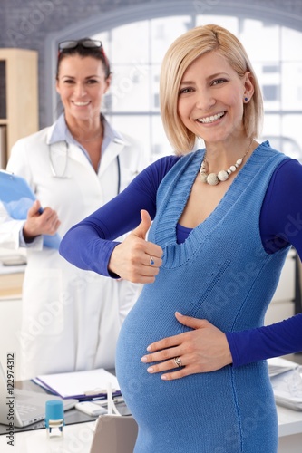 Happy pregnant businesswoman at doctor s office